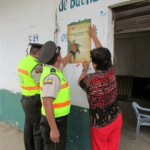 Policía Nacional y comunidad pegando afiches para preservar la palma de cera