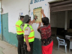 Policía Nacional y comunidad pegando afiches para preservar la palma de cera