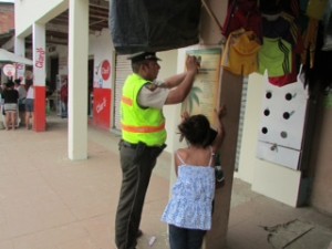 Uniformado junto a niños pegando afiche de prevenciónJPG